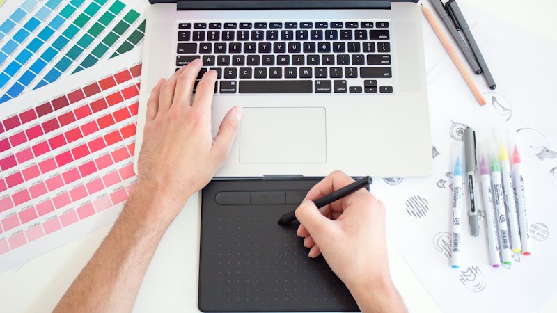 Person designing an interface on a drawing tablet and laptop