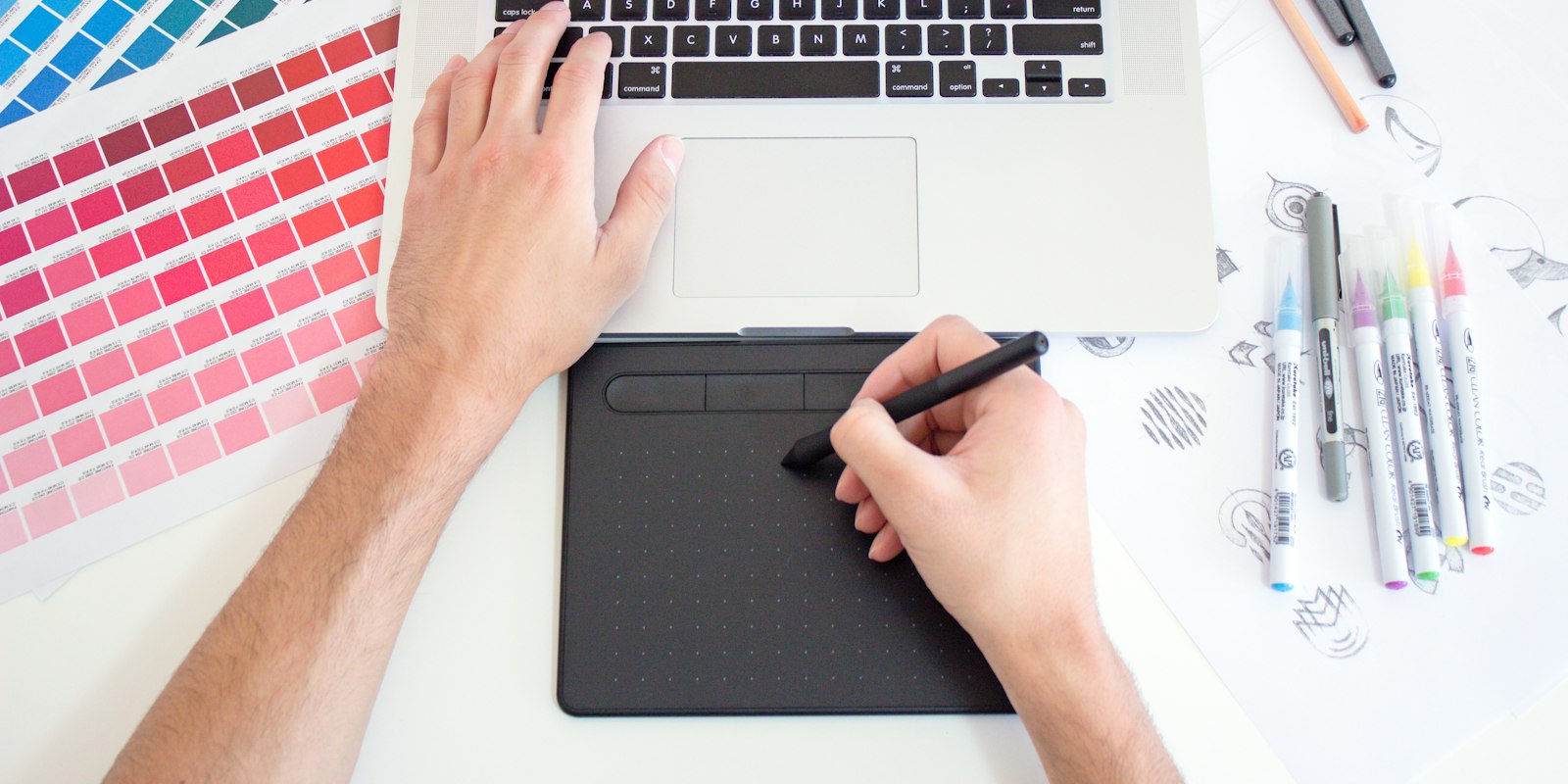 Person designing an interface on a drawing tablet and laptop