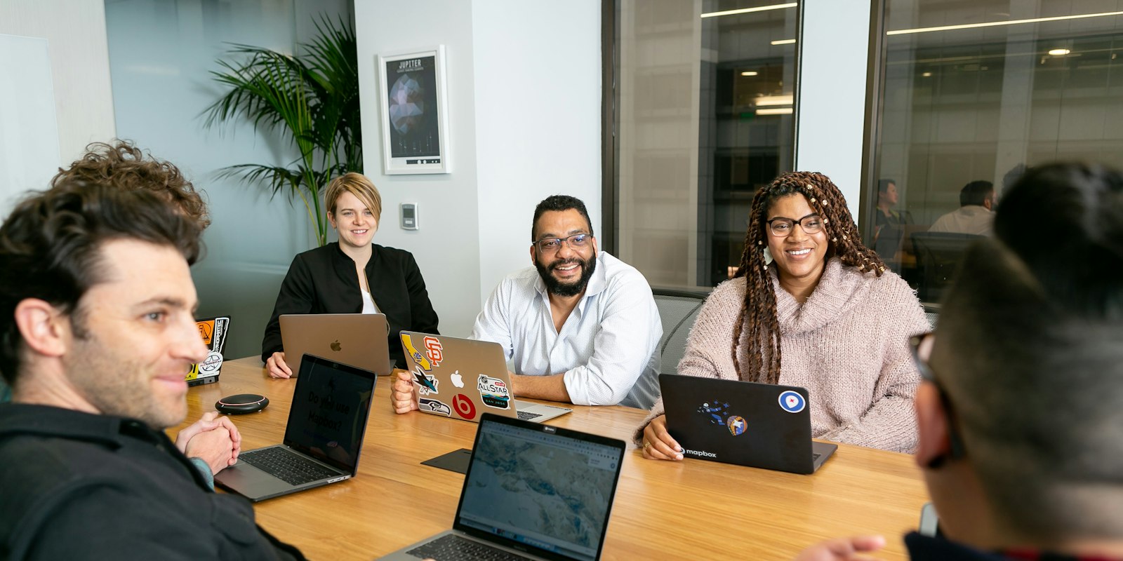 Four people working on laptops listening to a colleague
