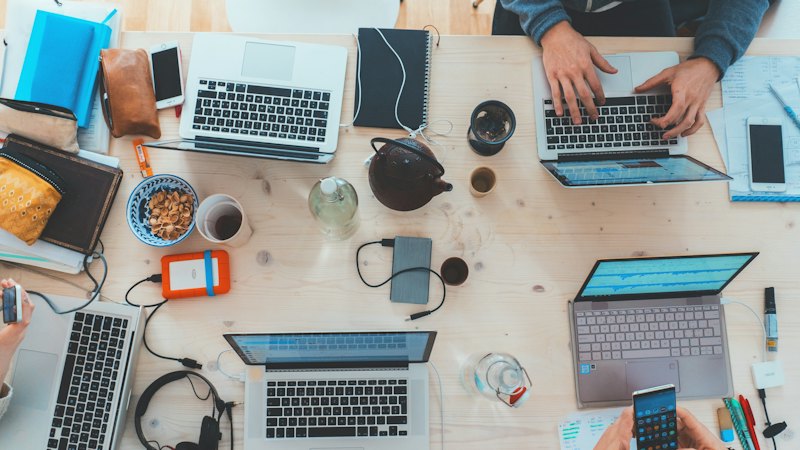People working on laptops around a shared table