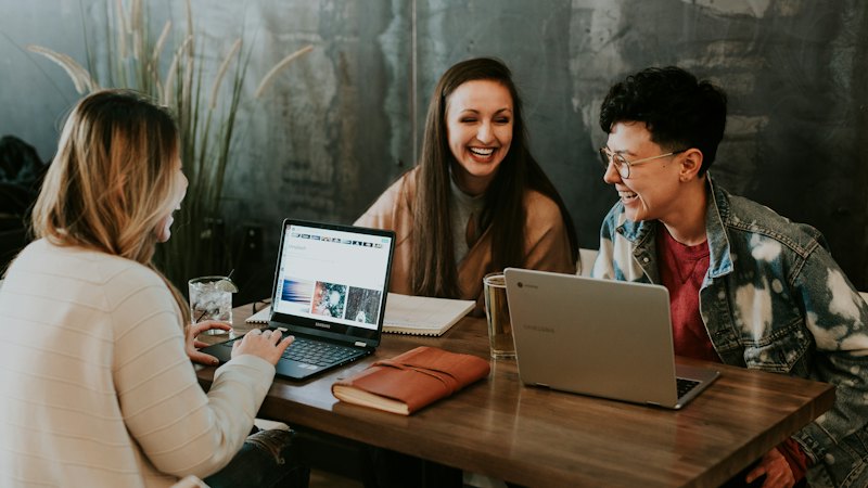 Three people learning together at a table with a laptop