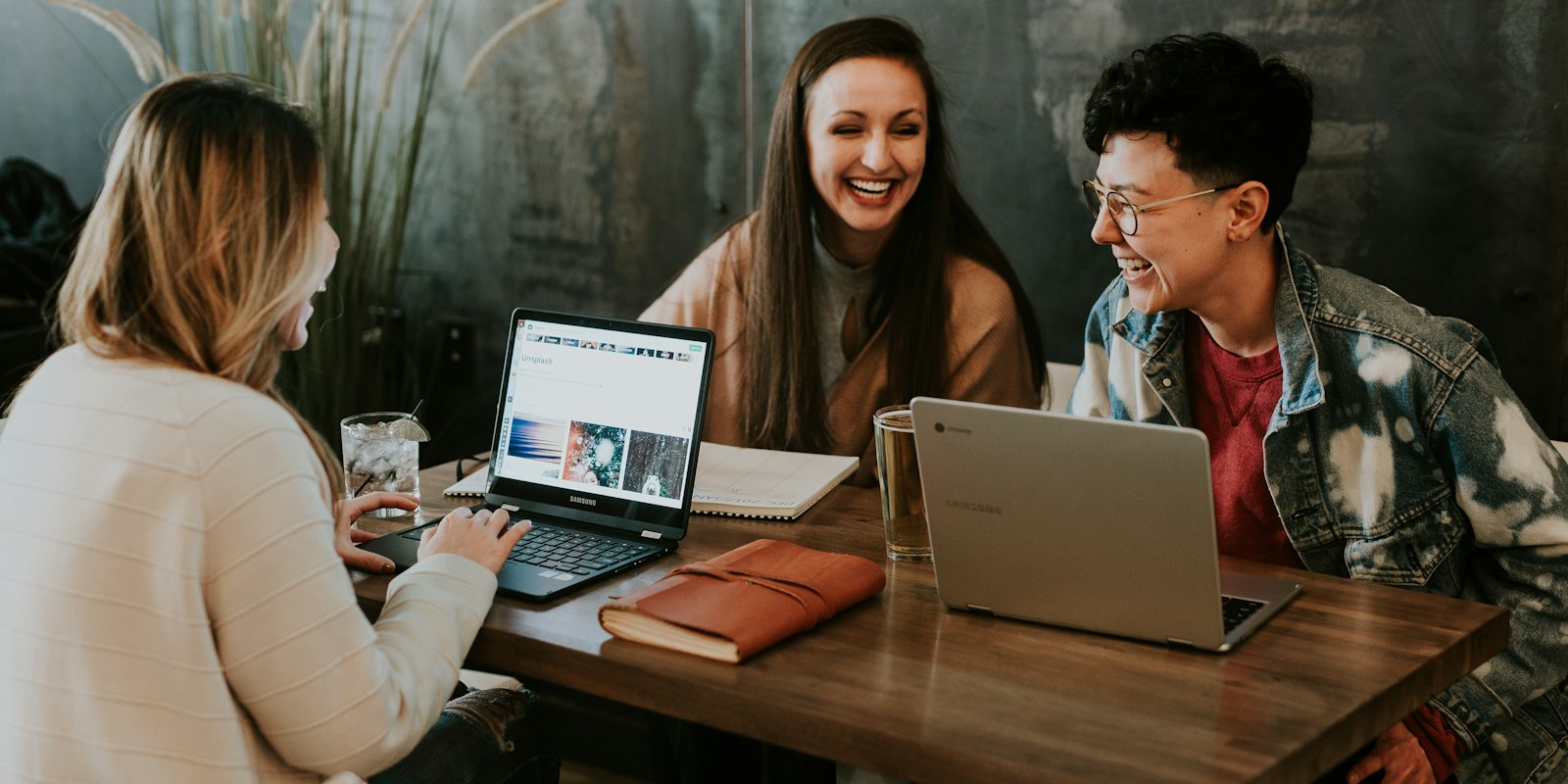 Three people learning together at a table with a laptop